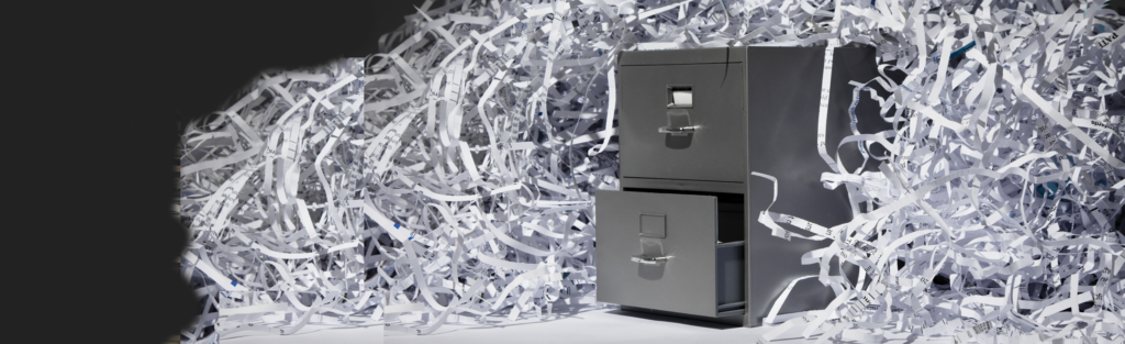 A photo of a file cabinet with shredded papers surrounding it. 